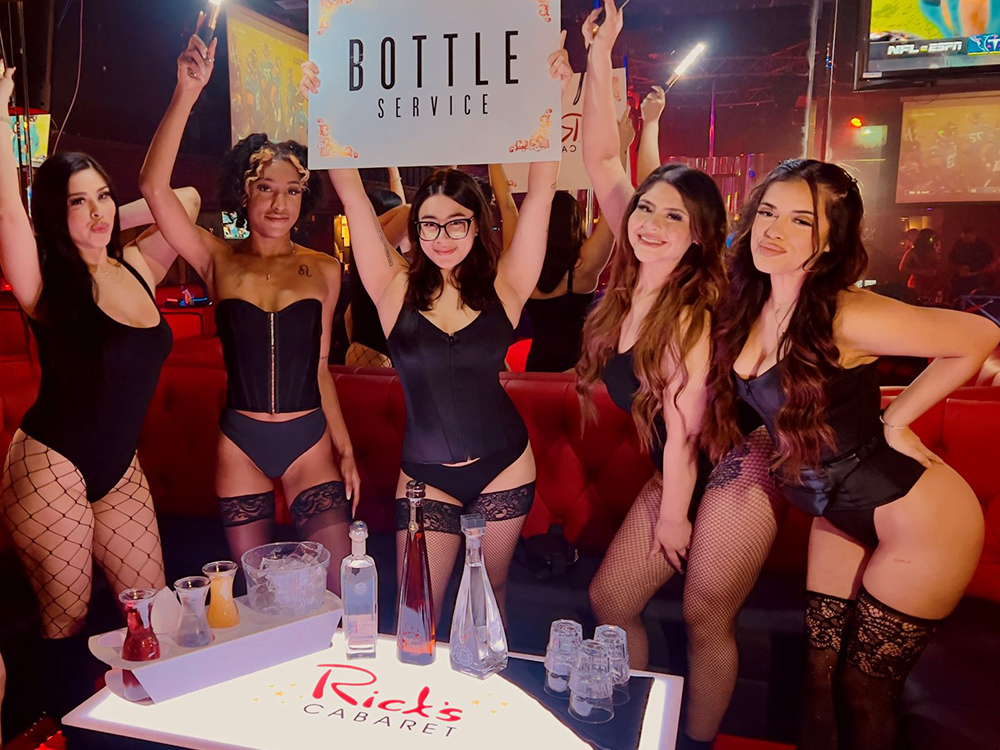 Four of Rick's sexy waitresses holding a Bottle Service sign